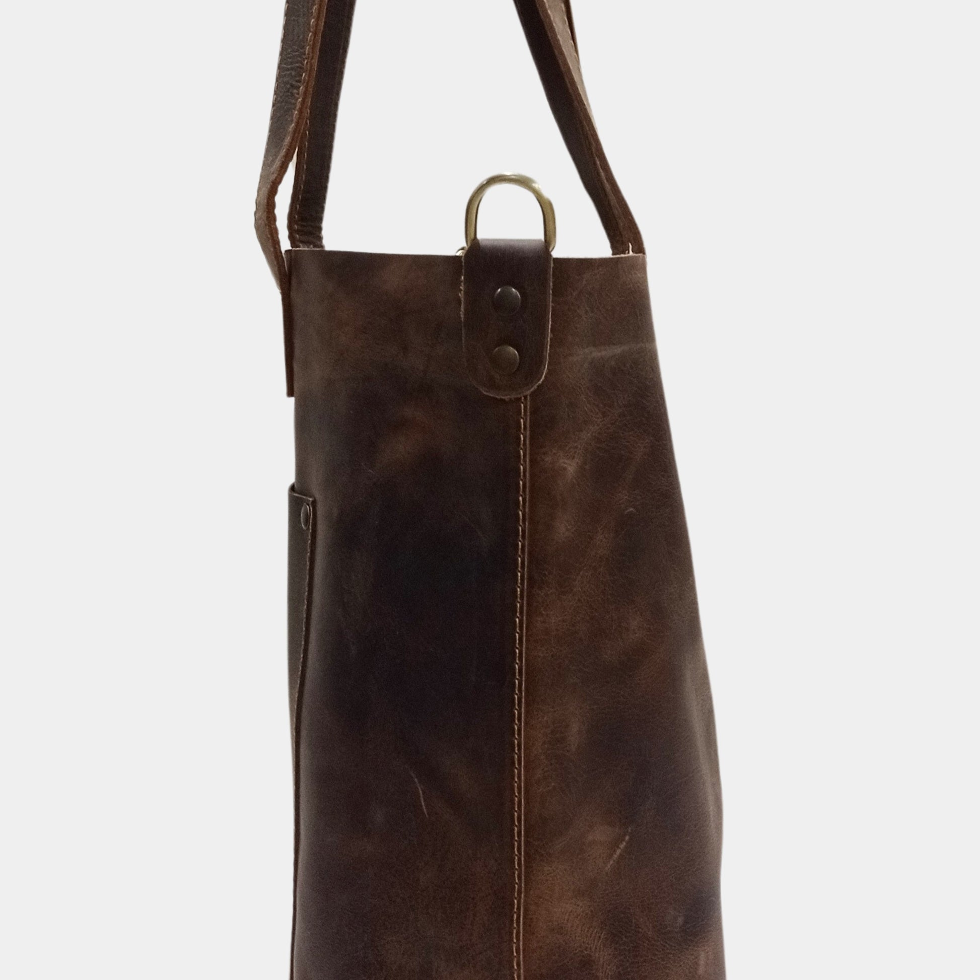 Brown leather bag with a strap on a light gray background