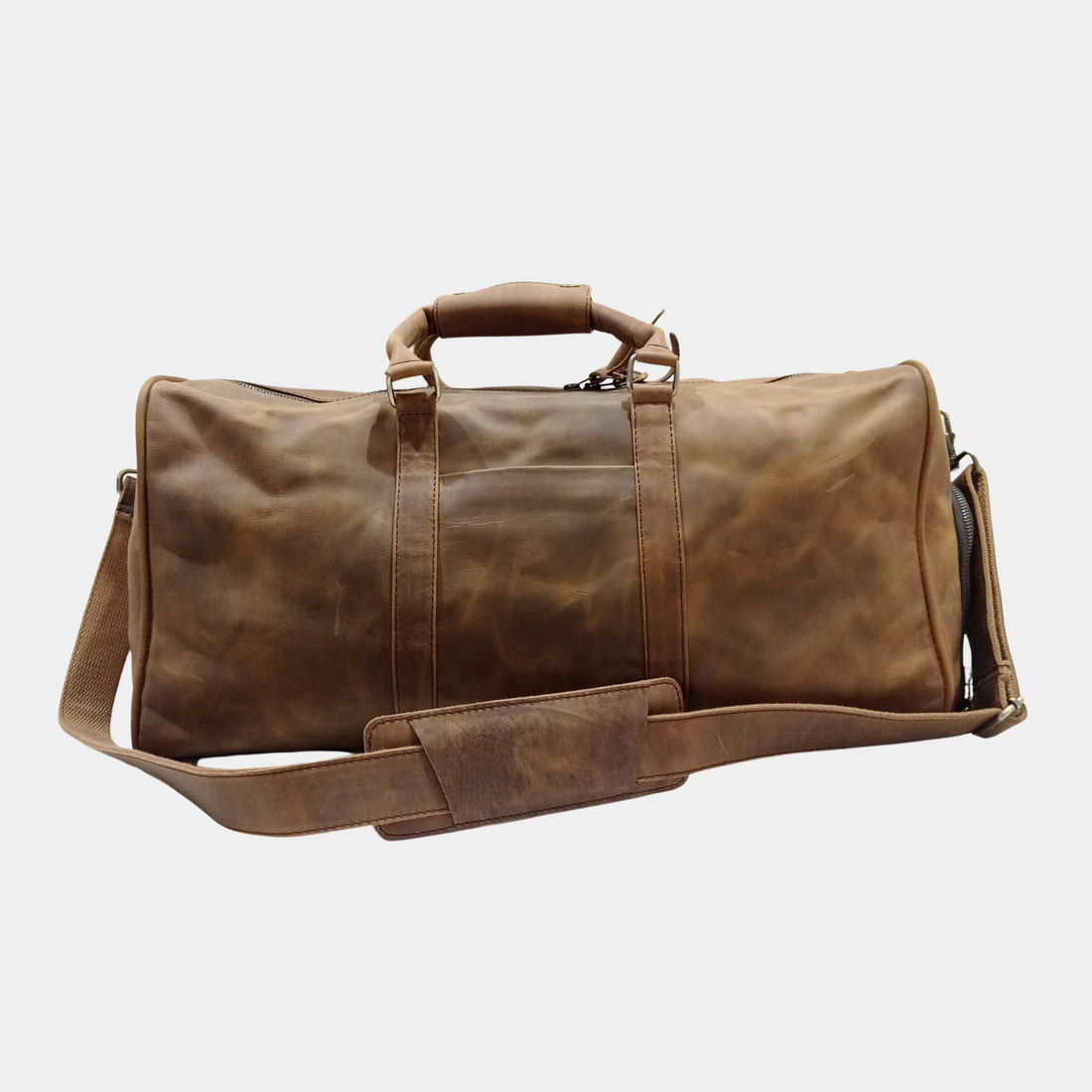 Brown leather duffle bag with sturdy handles and an adjustable shoulder strap, designed for weekend trips and stylish daily use.