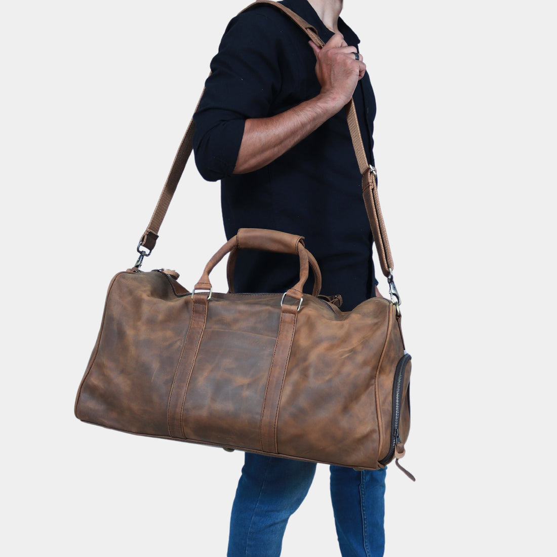 Brown leather duffle bag with sturdy handles and an adjustable shoulder strap, designed for weekend trips and stylish daily use.