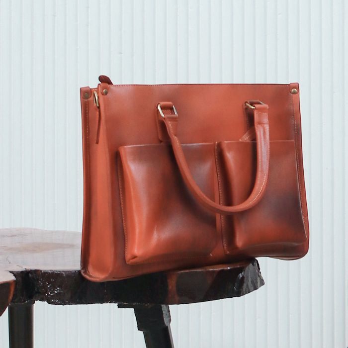 A female model with Harbour Classic Leather Messenger Bag in her hands while sitting on sofa