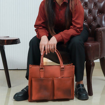 A female model with Harbour Classic Leather Messenger Bag in her hands while sitting on sofa