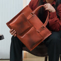 A model holding the Harbour Classic Messenger in her hands diagonally while holding it with soft leather handles