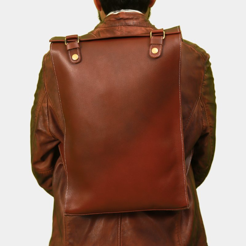 A guy sitting in chair posing High-quality leather Executive Edge backpack in classic brown, durable and versatile