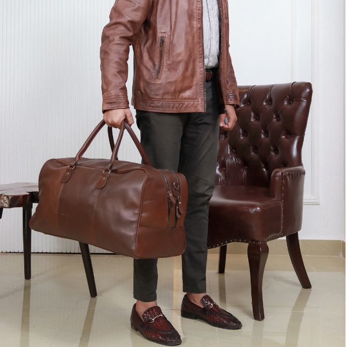 A Model posing with brown Tasman Travel Duffle Bag while sitting in sofa