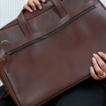 A model holding Dark Brown Nomad Essential Messenger Bag diagonally in hers hands 