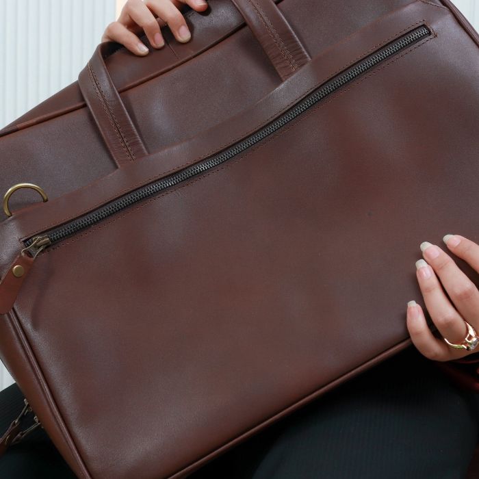 A model holding Dark Brown Nomad Essential Messenger Bag diagonally in hers hands 