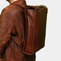 Model Posing Stylish Brown Executive Edge leather backpack while wearing using adjustable straps 