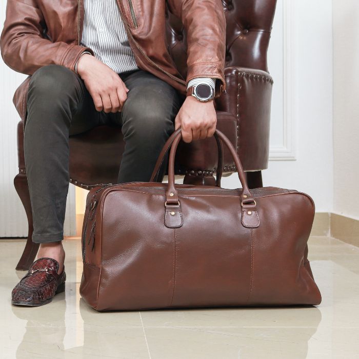 A Model posing with brown Tasman Travel Duffle Bag while sitting in sofa