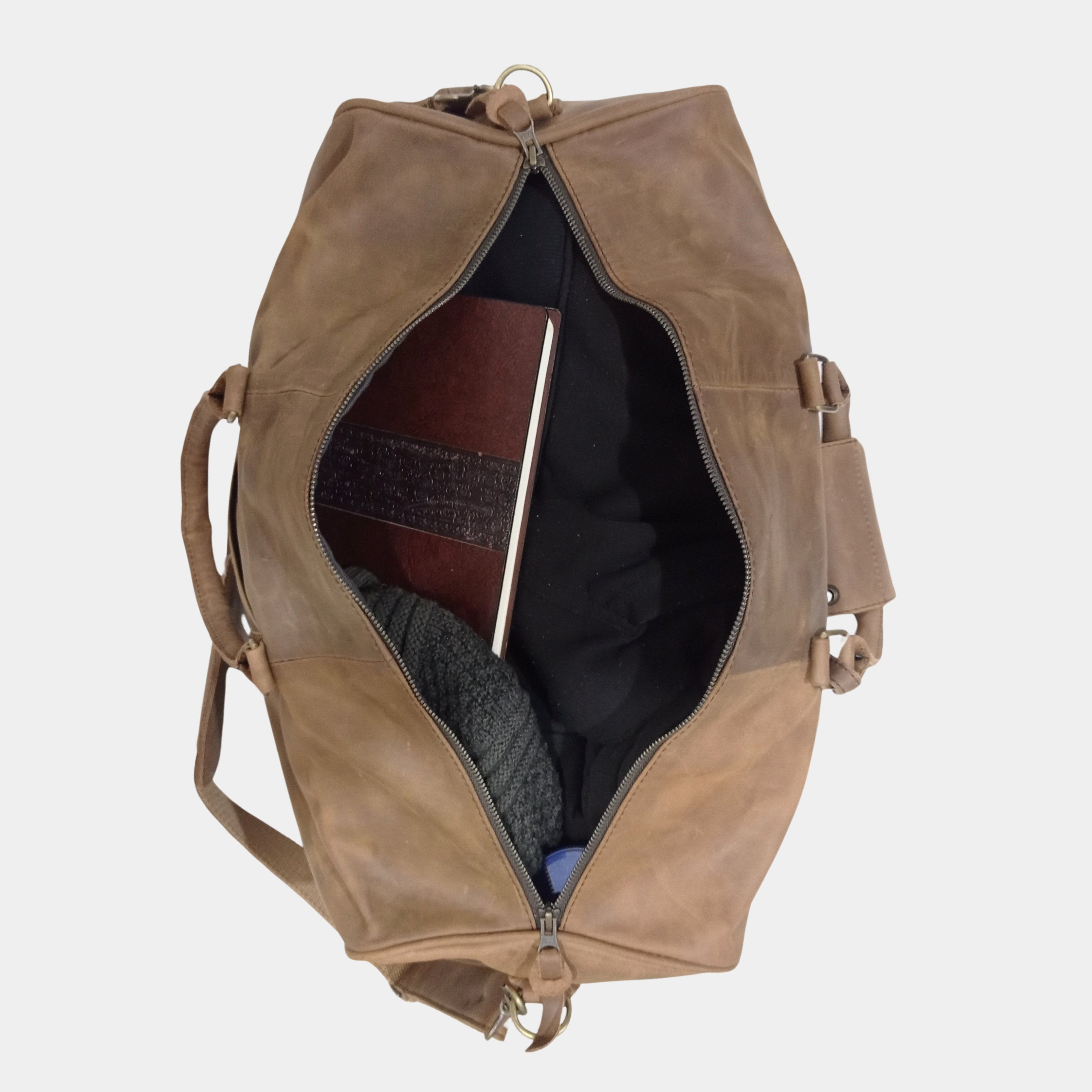 Packed inside view of Eyre Brown Leather Duffle showing cloths nicely arranged with a notebook placed on top