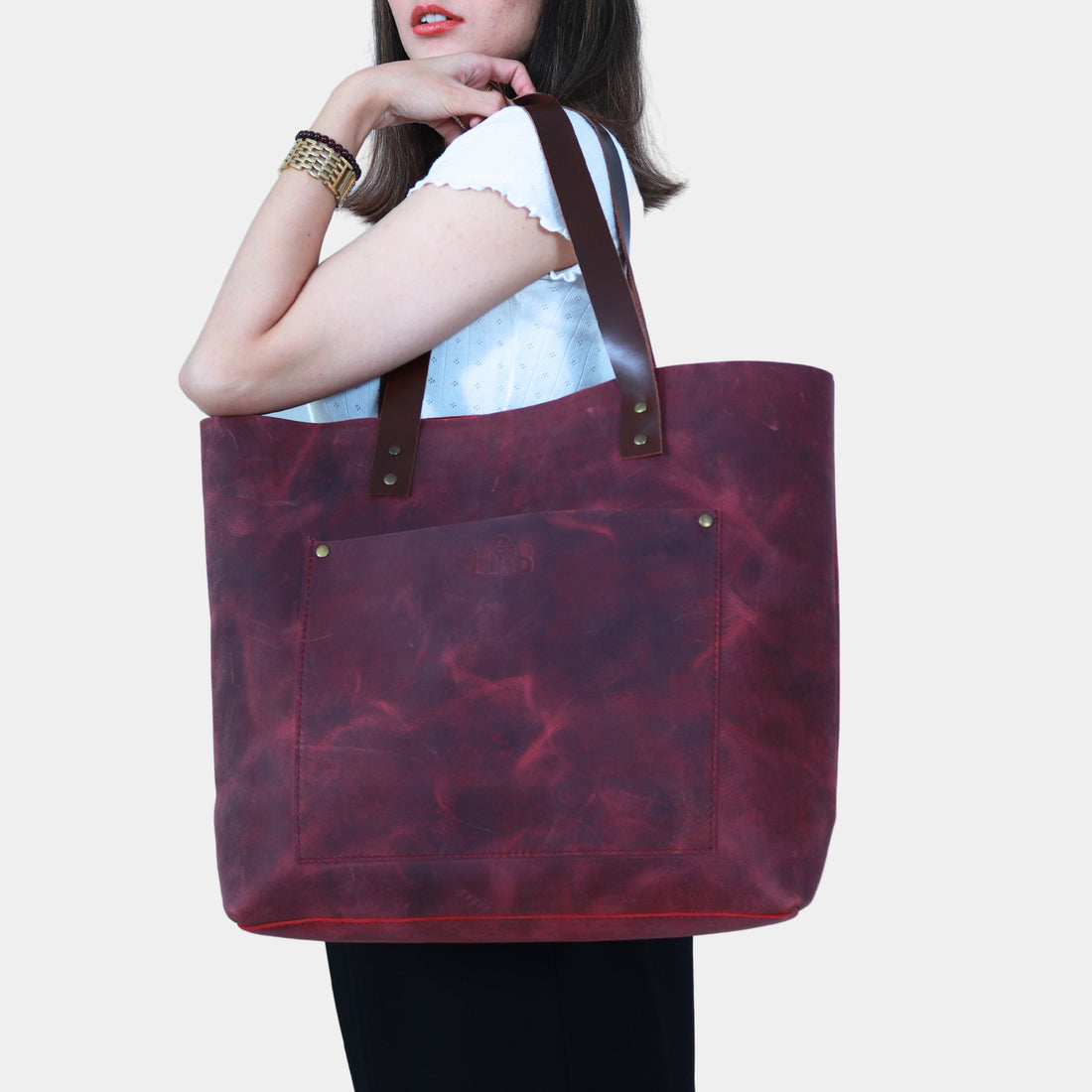 Girl in black dress elegantly slinging Willow Leather Tote with Soft dark brown bridle leather handles