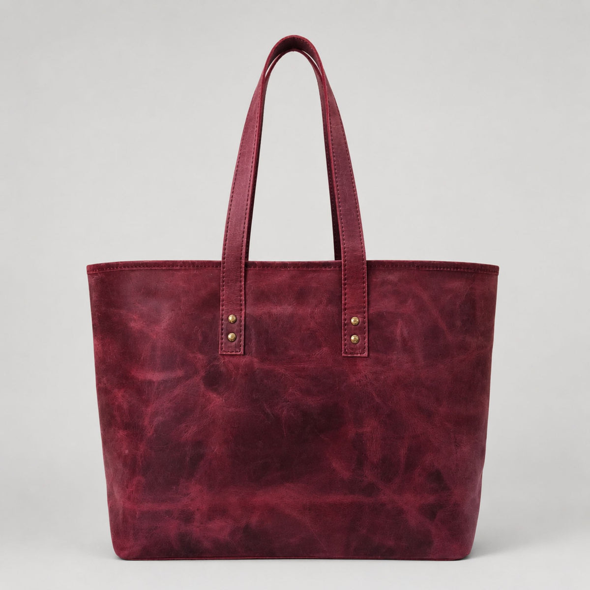 Premium vintage burgundy leather handbag featuring a smooth, clean texture face with heavy duty stitched handles and antique gold metal rivets