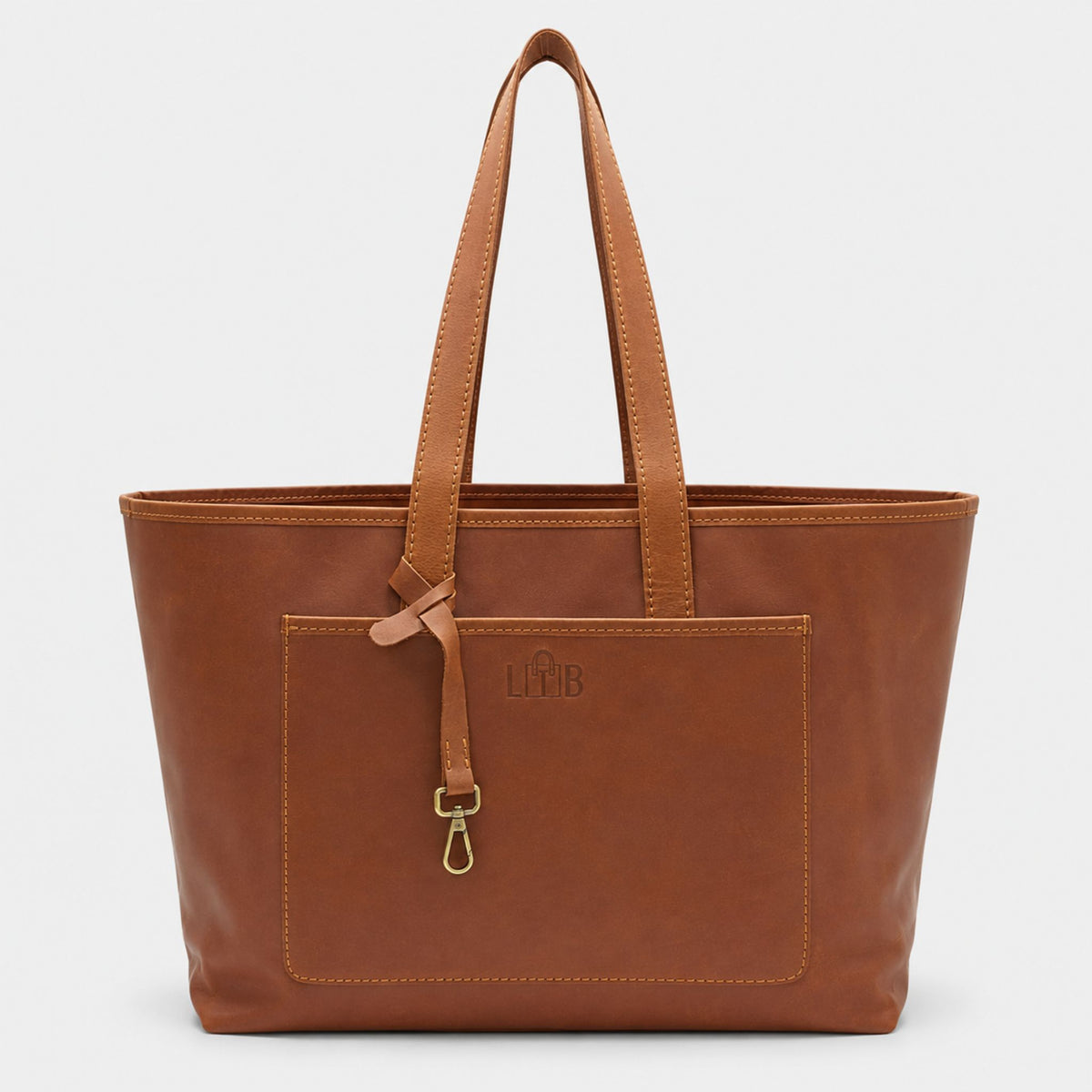 Front view of the Emily Leather Tote in tan brown full grain leather, showing a large front exterior pocket and a brass key leash strap