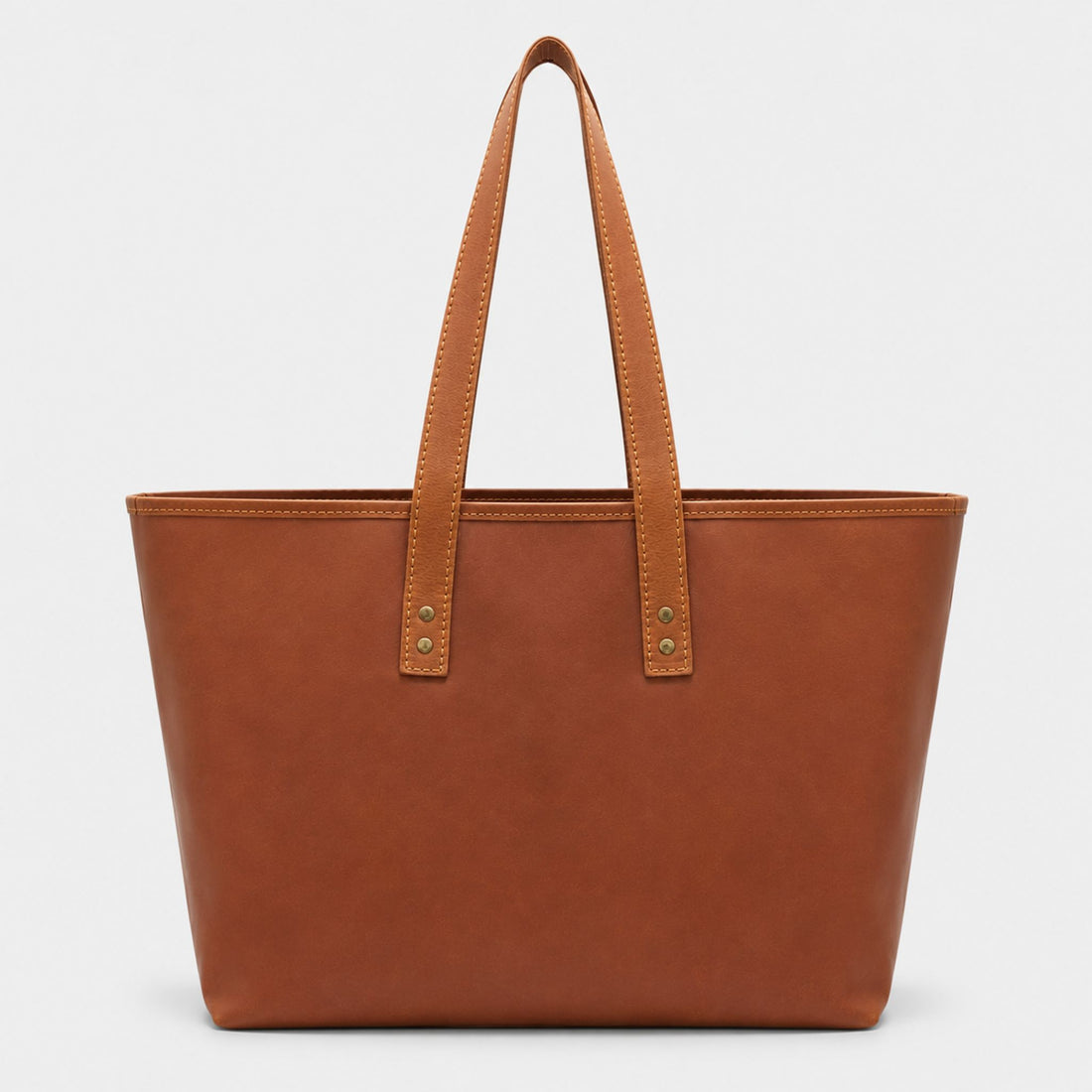 Front view of the Emily Leather Tote in tan brown full grain leather, showing a large front exterior pocket and a brass key leash strap